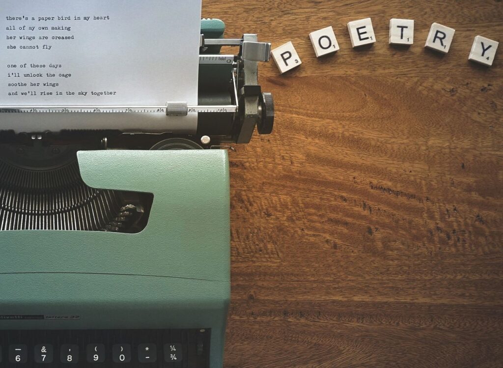 Home A typewriter creates poetic lines on paper amidst Scrabble tiles spelling 'POETRY'.
